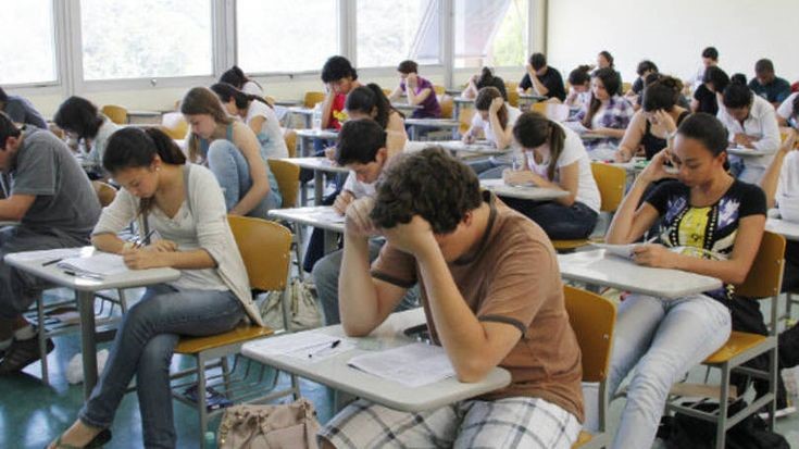 Sala de aula com candidatos fazendo uma prova de concurso público de nível médio